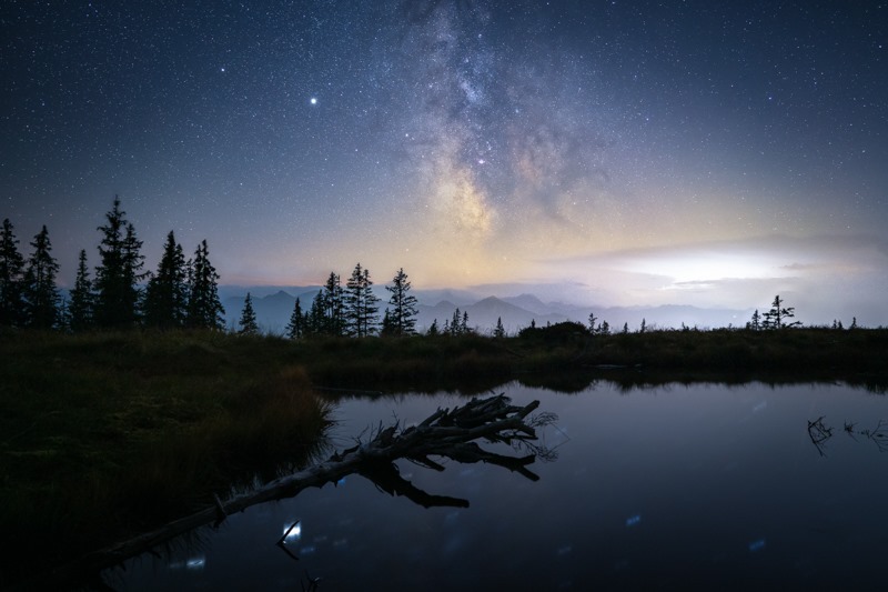 Astronomy Winner July - A lake under a starry sky with a forest in the background